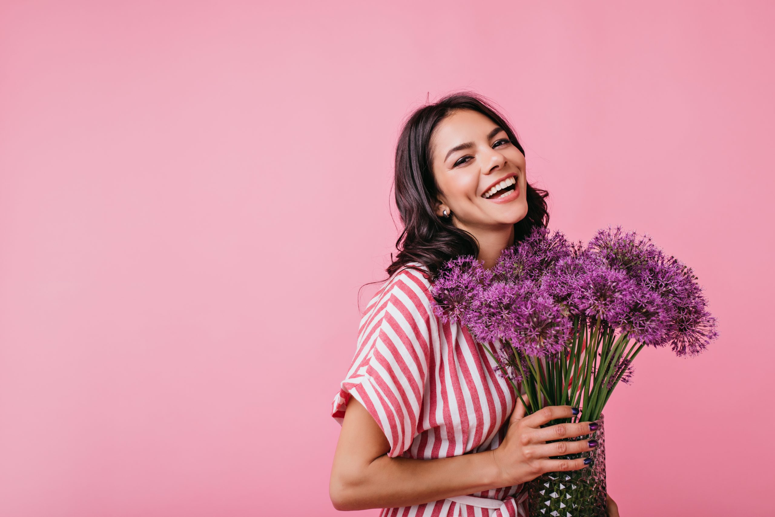 positive brunette with dimples radiates joy. snapshot of cute curly lady with lovely huge purple flowers.